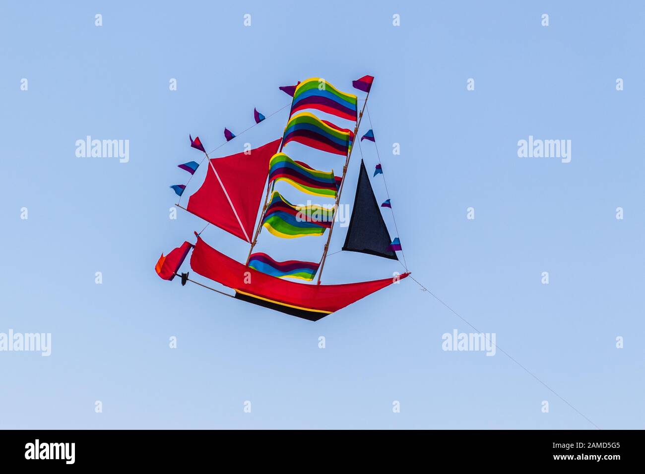 Rainbow Coloured Kite in Form eines hohen Schiffes am Himmel, Bali, Indonesien. Stockfoto