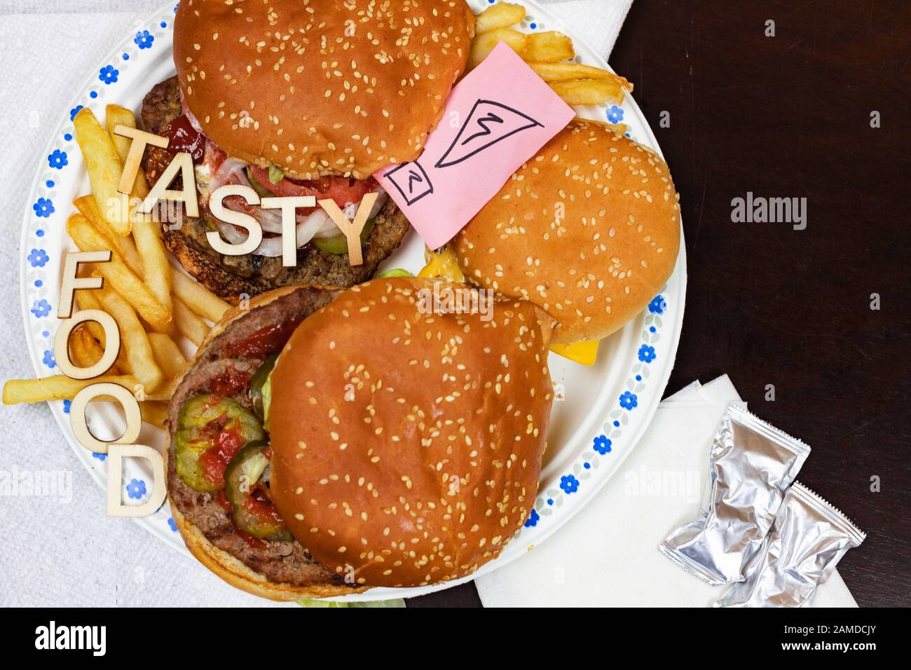 Saftige Burger und Pommes frites auf einem Papierteller mit Worten LECKERES ESSEN auf Burgern. Stockfoto