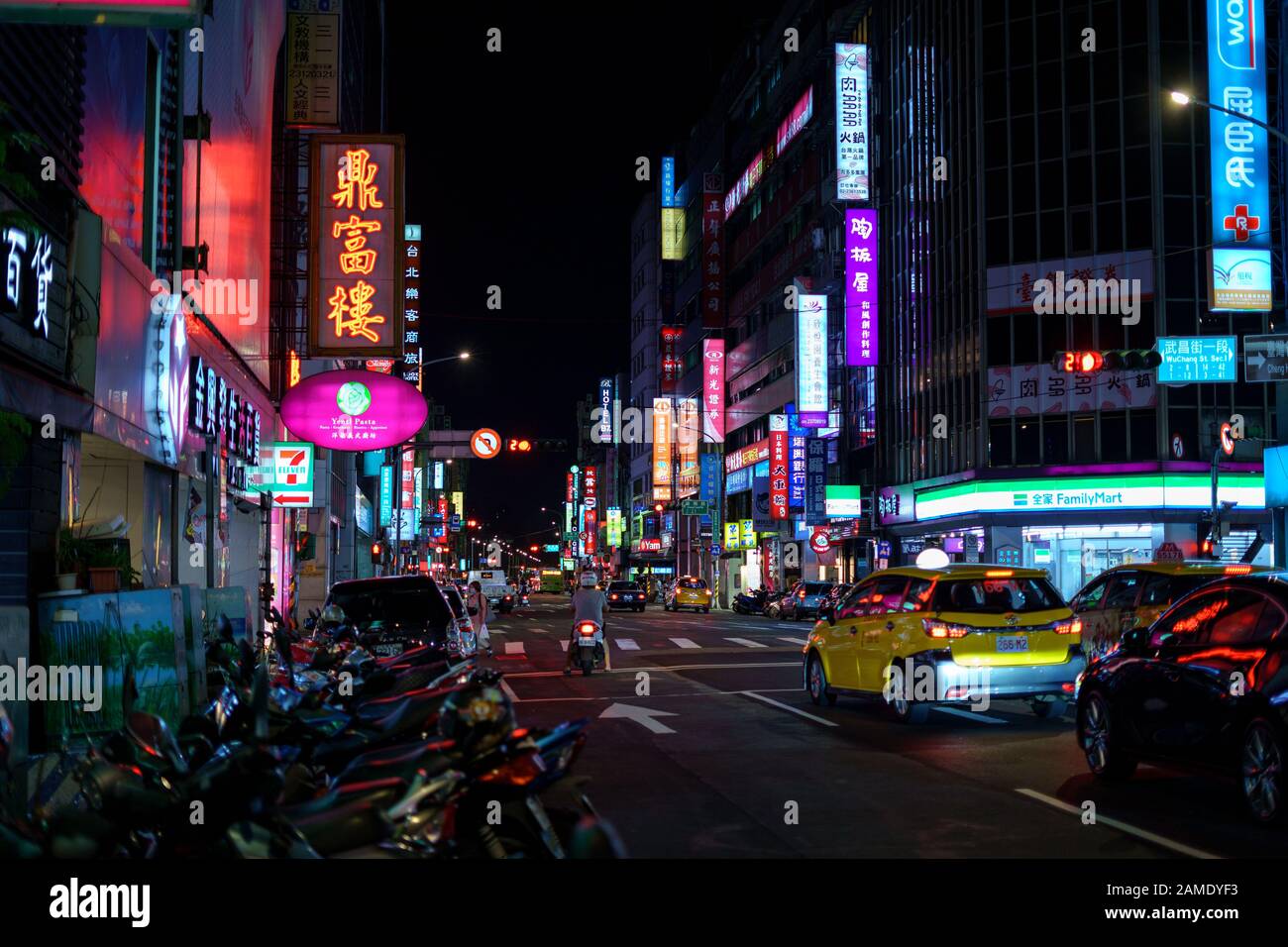 Belebte städtische Straße in der Nacht, beleuchtet von bunten Werbe-Neon-Zeichen mit chinesischen Schriftzeichen. Stockfoto