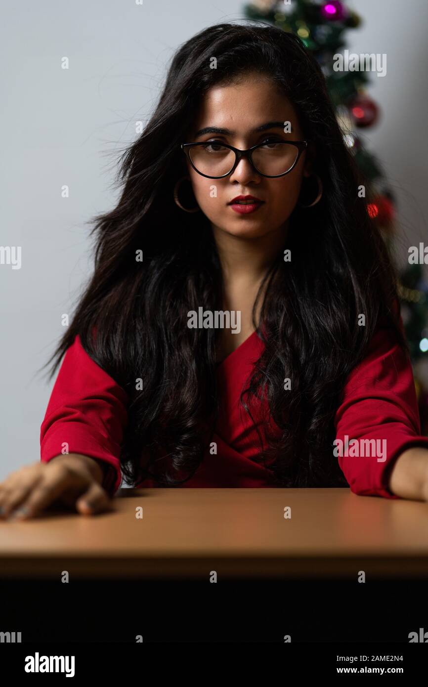 Elegante Dame in rotem Kleid über weihnachtsbaum leuchtet Hintergrund. Stockfoto