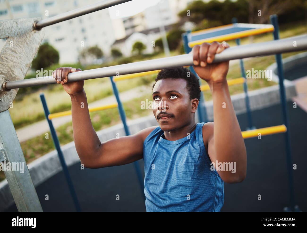 Portrait des entschlossenen, sportlichen jungen afroamerikanischen Mannes führt Pull-Ups-Übungen durch, um die Muskeln im Sportpark im Freien zu stärken Stockfoto