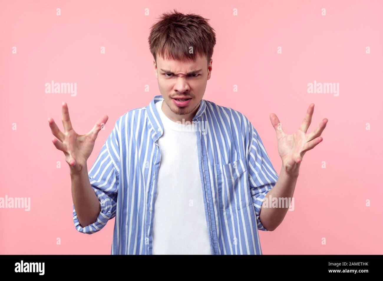 Porträt eines aggressiven, verrückten, braun-haarigen Mannes mit kleinem Bart und Schnurrbart in einem lässigen Hemd, das die Hände im Zorn hebt und Kamera mit wütender FAC betrachtet Stockfoto