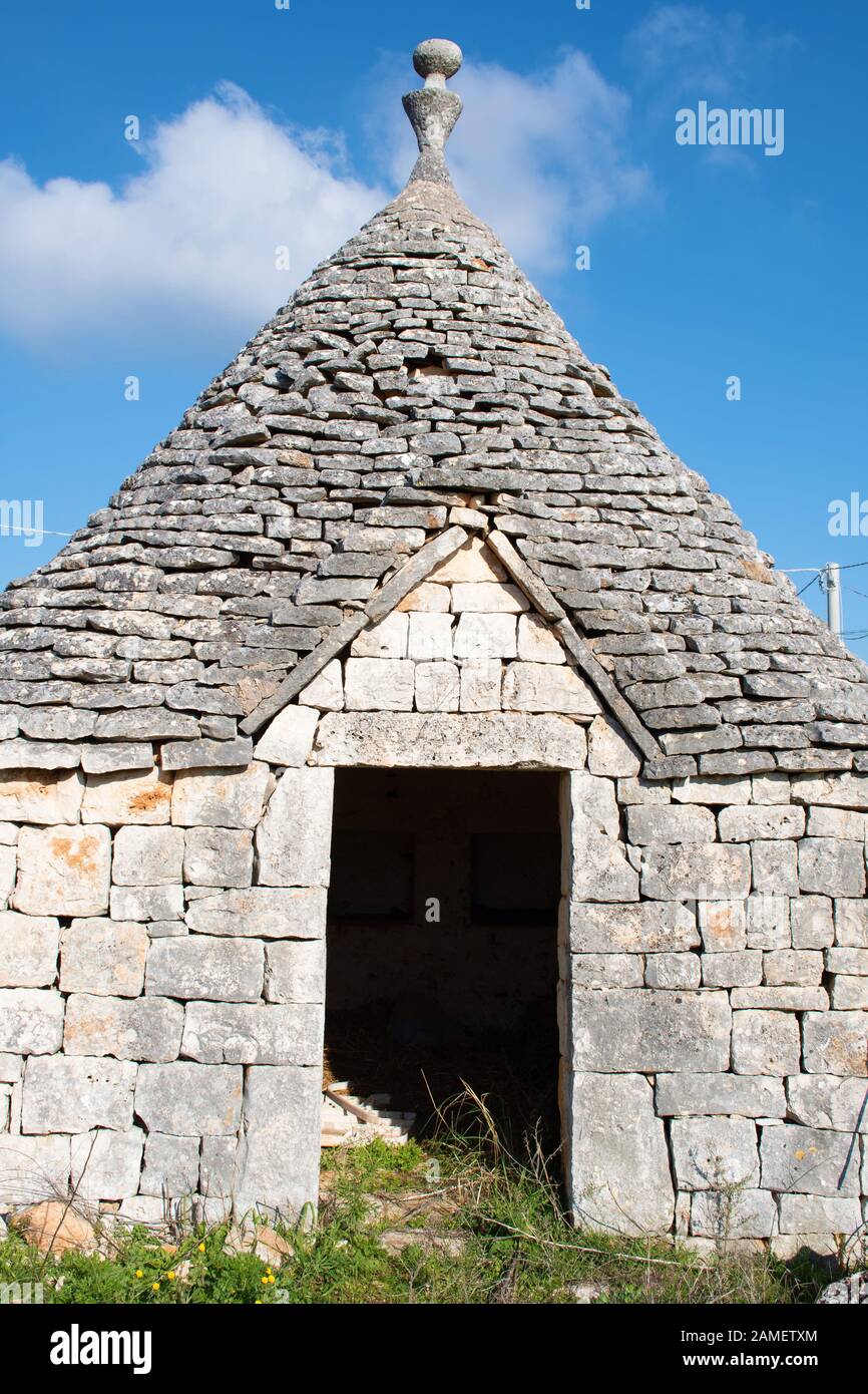 Trullo Haus mit Eingang, traditionelle alte Häuser und alte Steinmauer in Apulien, Italien, Europa, vertikal Stockfoto