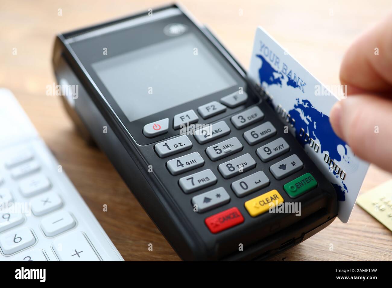 Halten Sie die Kreditkarte mit der Schließzeit des POS-Terminals in der Hand Stockfoto