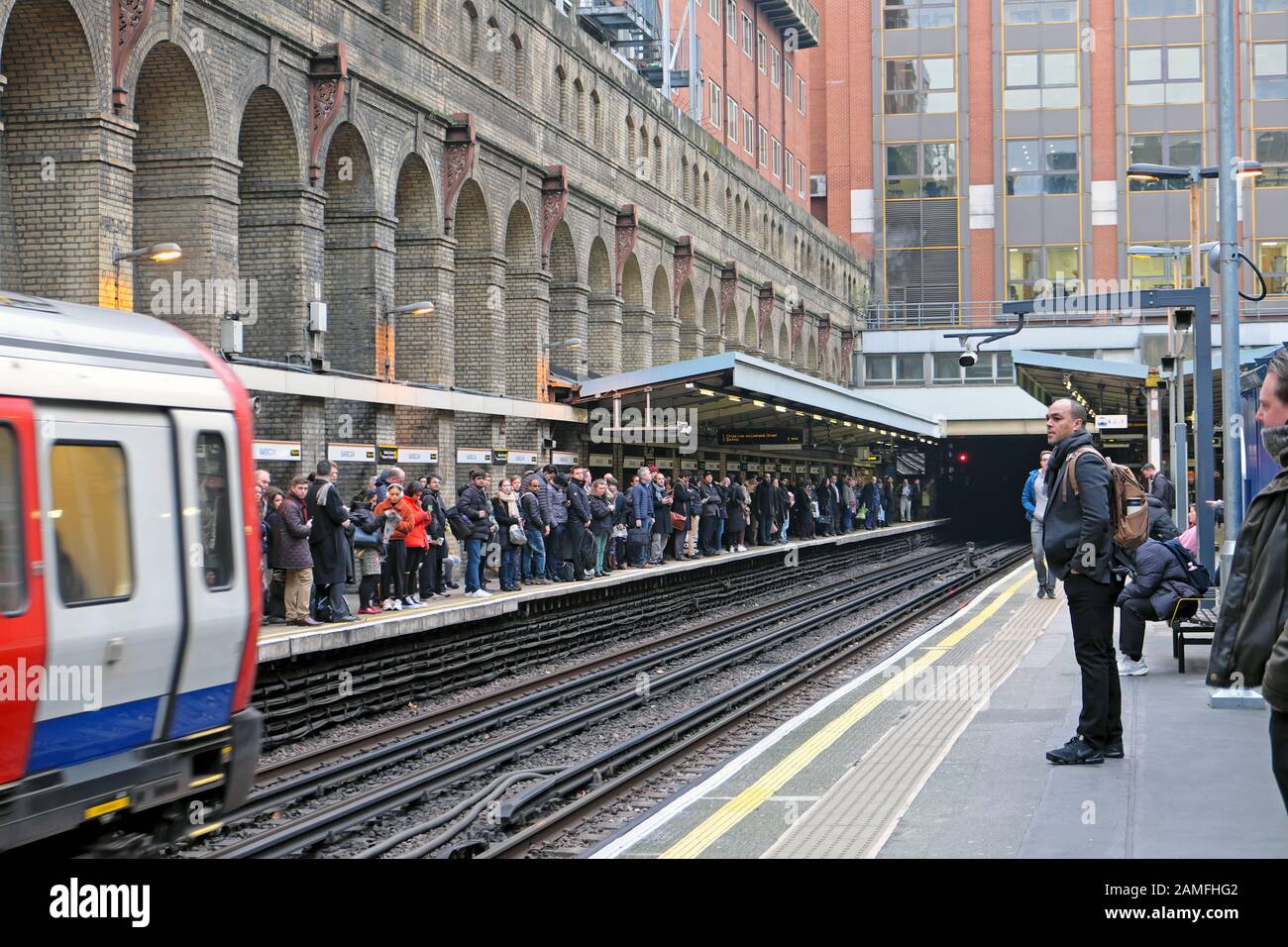 Personen, die auf dem Bahnsteig am U-Bahnhof Barbican Station & Train auf Bahngleise warten, nähern sich in London EC1 England UK KATHY DEWITT Stockfoto