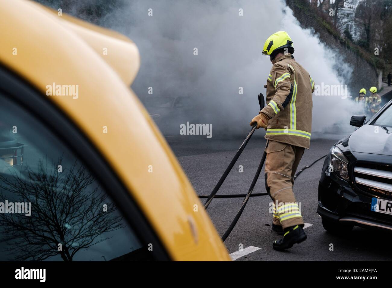 Mitglieder des Kent Fire and Rescue Service löschen einen Autobrand auf Rochester Esplanade, Kent, England, Großbritannien Stockfoto