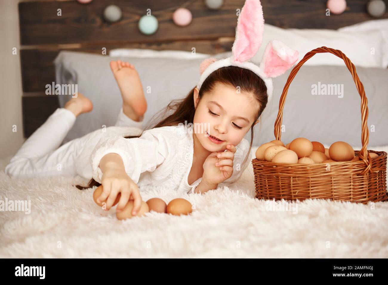 Glückliches Kind, das im Schlafzimmer mit Eiern spielt Stockfoto
