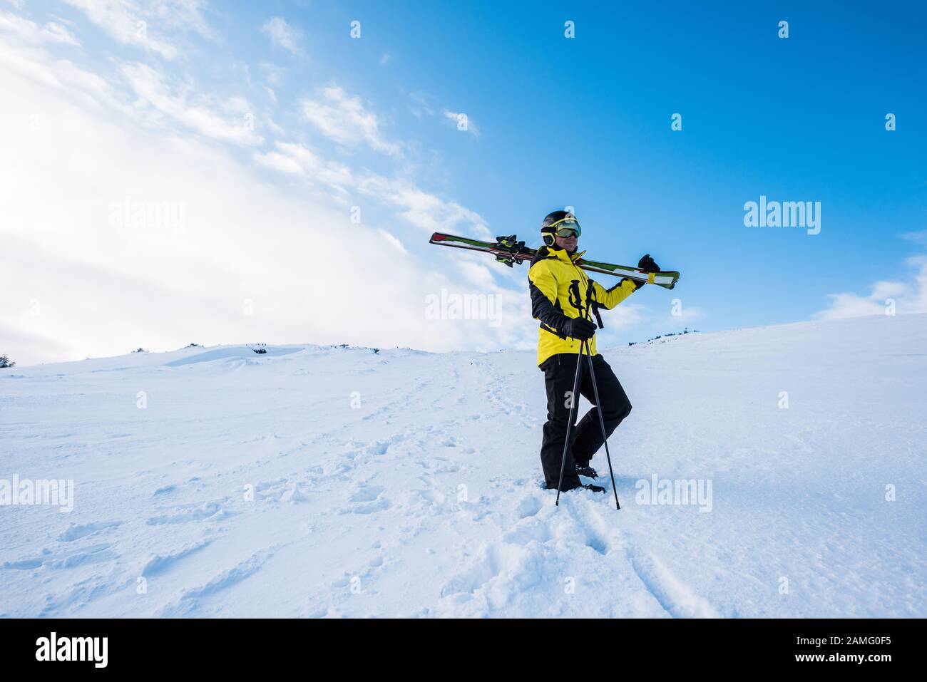 Sportler im Helm mit Skistöcken auf Schnee in den Bergen stehen Stockfoto