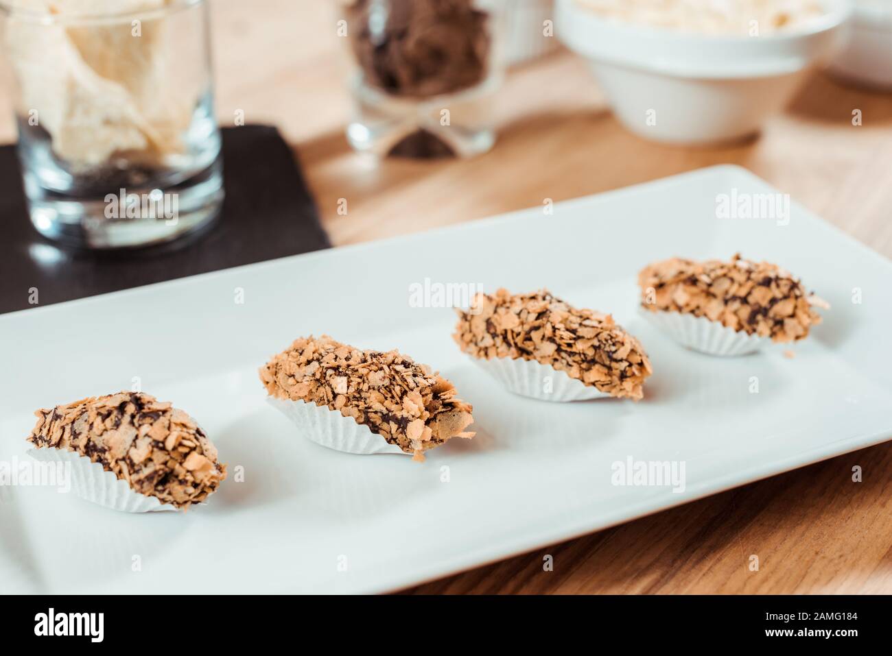 Selektive Fokussierung von zubereiteten Schokolade-Süßigkeiten mit Flocken auf Platte Stockfoto