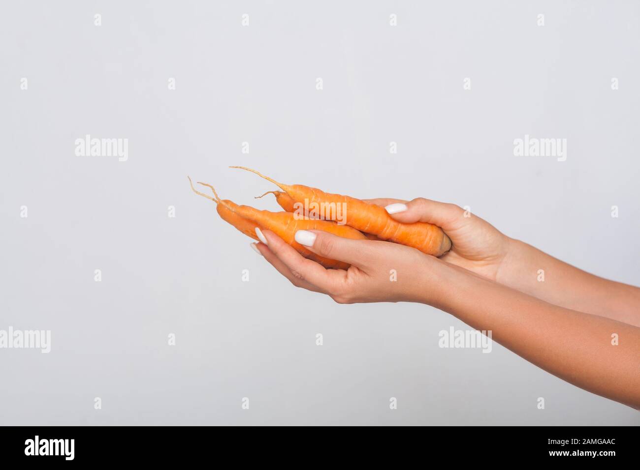 Nahaufnahme der weiblichen Hände mit Orangenkarotten, frischem Rohgemüse, Konzept der gesunden Ernährung mit Vitaminen Beta-Karotin, vegetarische Ernährung, niedrige calo Stockfoto
