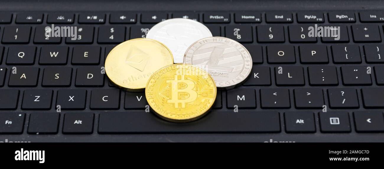 Bitcoin-, Litecoin-, ätherische und Ripple-Münzen auf einem schwarzen Computercurboard mit weißen Buchstaben. Stockfoto