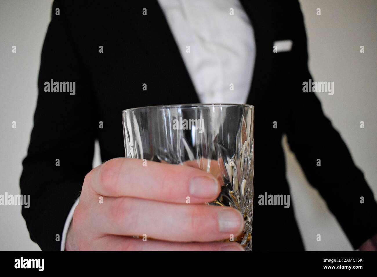 Nahaufnahme eines Mannes in einem schwarzen Tuxedo-Cheerleading mit einem Whiskyglas Stockfoto