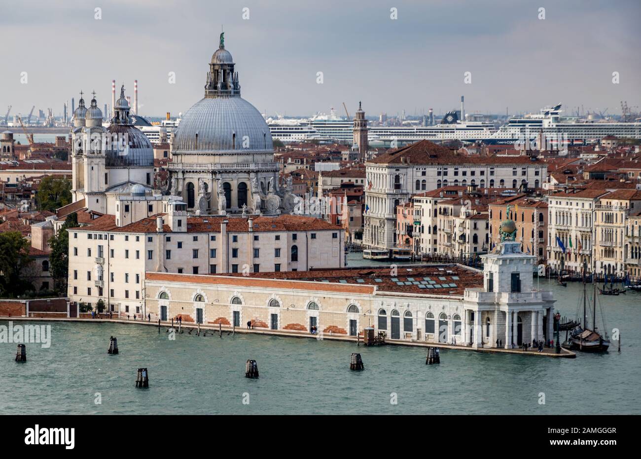 Luftaufnahme der Salute in Venedig mit mehreren großen Kreuzfahrtschiffen und der chemischen Industrie der U-Bahn, die die Skyline im Hintergrund dominiert. Stockfoto