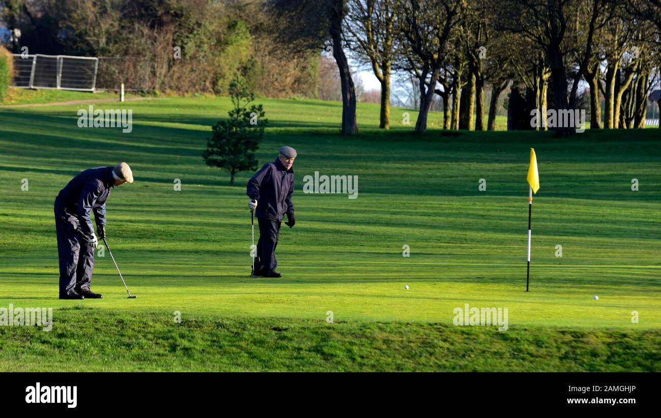Zwei Rentner, die an einem sonnigen Wintermorgen Golf spielen, West hallam, Ilkeston, Nottingham, England, Großbritannien Stockfoto