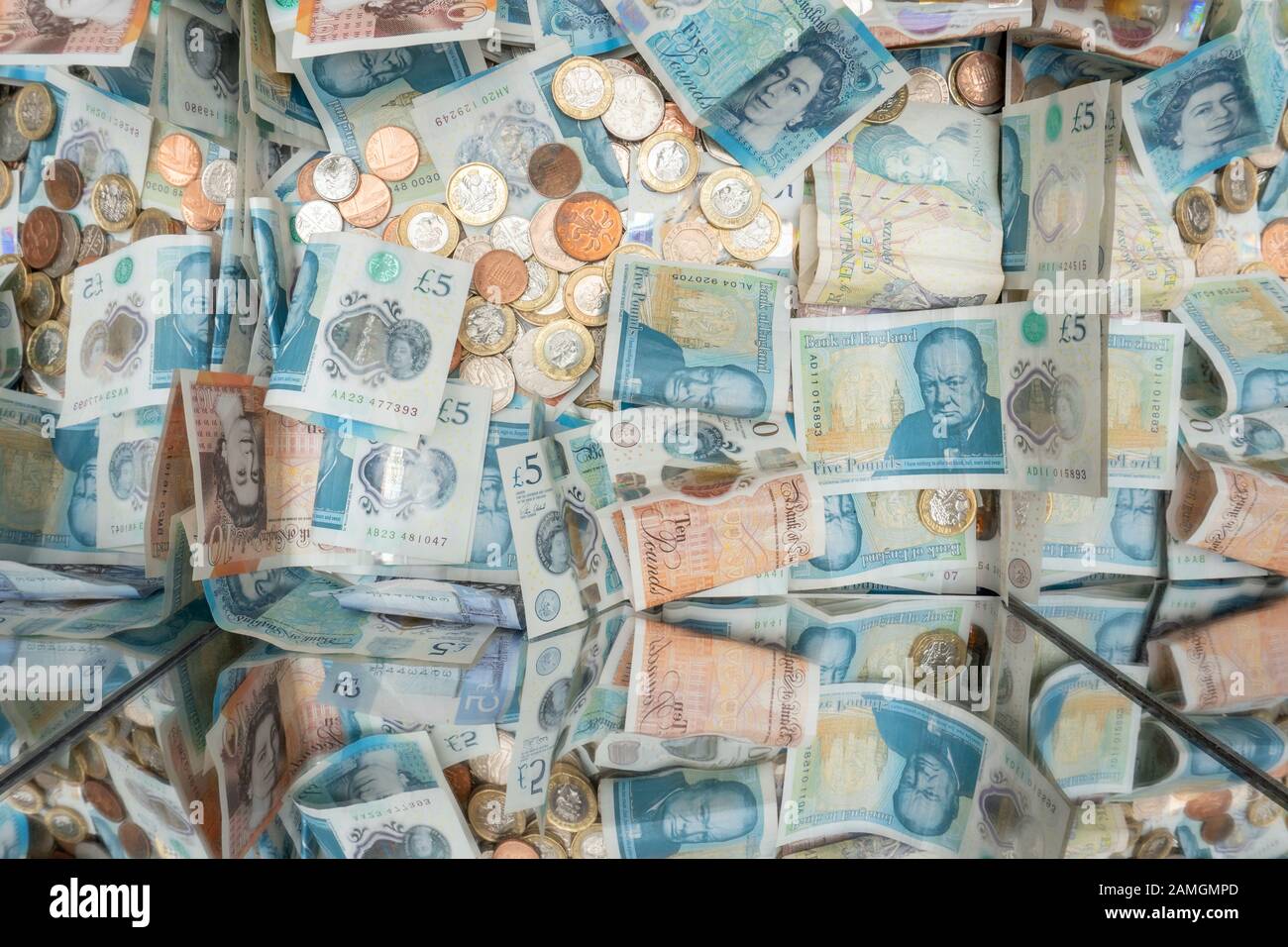 Verschiedene Stückelungen britischer Sterling Münzen und Banknoten in einem Spendenkasten, Liverpool, England Stockfoto