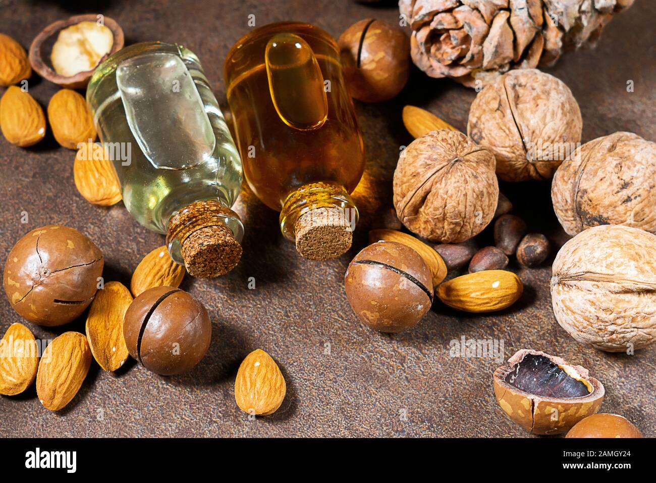 Natürliche Seren. Kosmetik- und Heilöl aus Macadamia, Mandeln, Walnüssen, Kiefernnüssen auf braunem Grund. Stockfoto