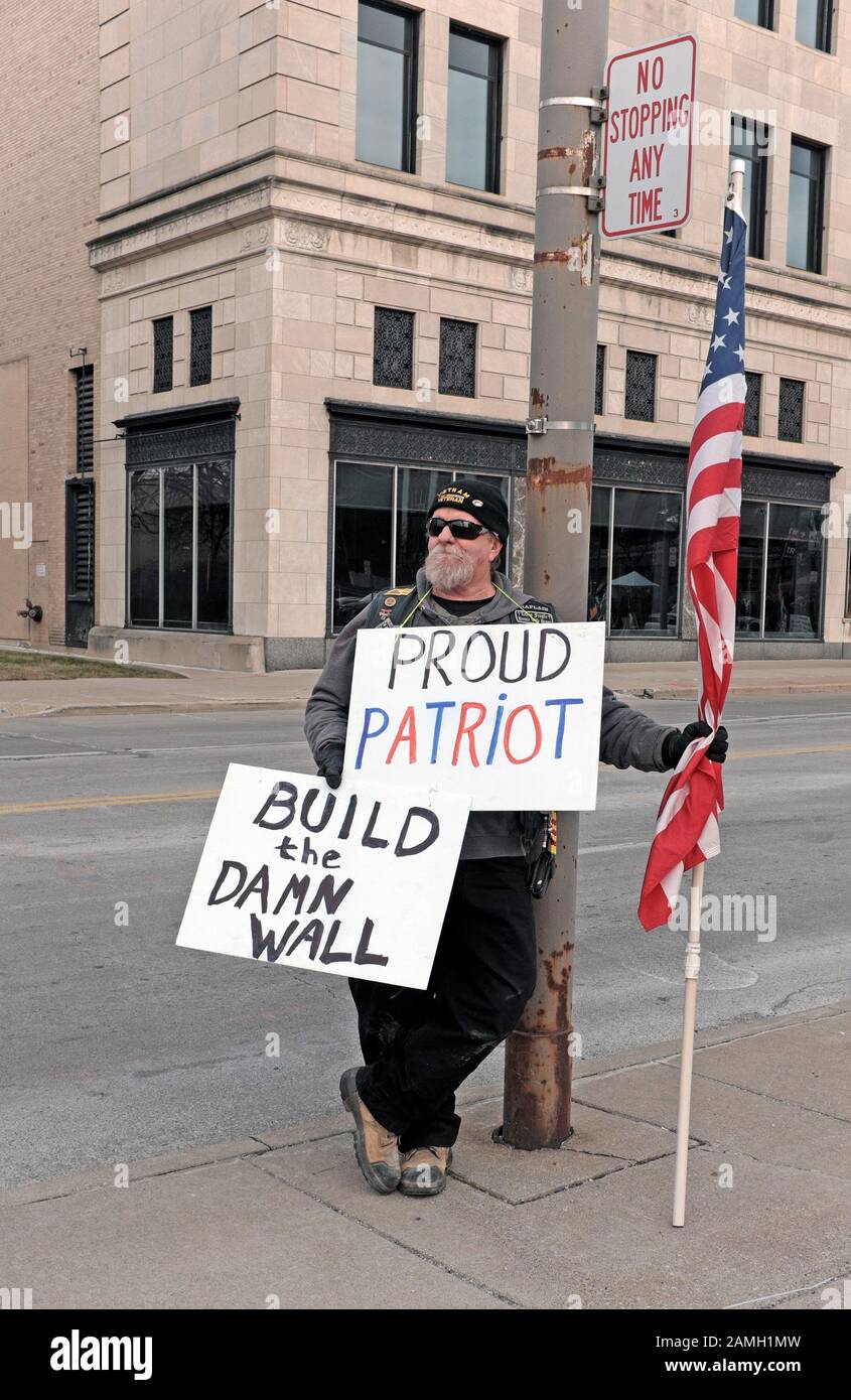 Ein Trump-Anhänger steht mit Zeichen, die "Proud Patriot" und "Build the Damn Wall" auf einer Straße in Toledo, Ohio, USA während einer politischen Kundgebung Trumps angeben. Stockfoto