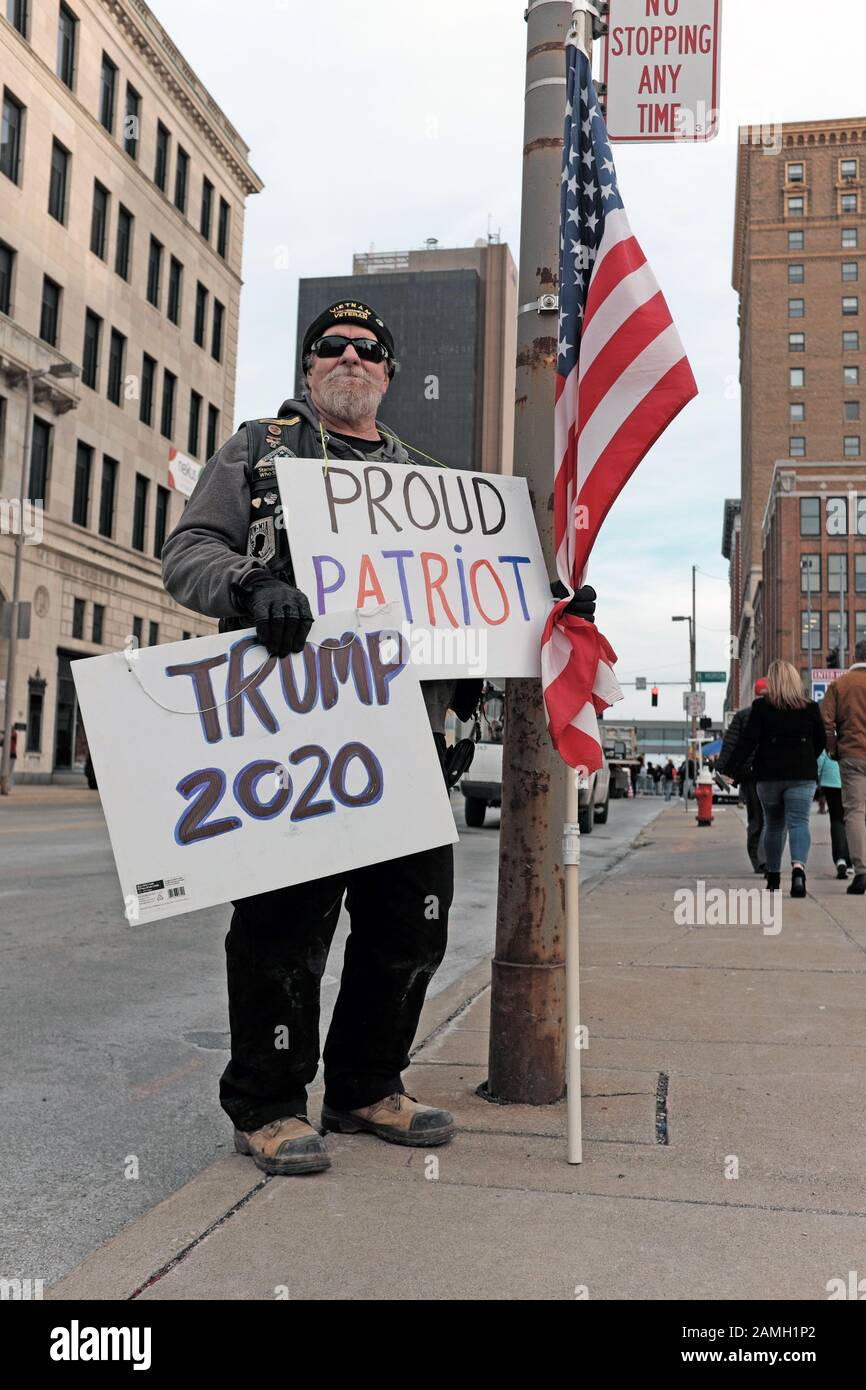 Ein selbsterklärter, stolzer amerikanischer Patriot hält eine amerikanische Flagge zusammen mit den Schildern "Trump 2020" und "Proud Patriot" in Toledo, Ohio, USA. Stockfoto