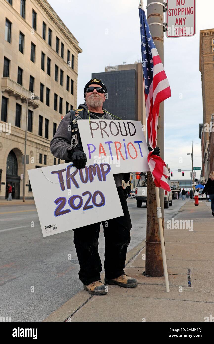 Ein Trump-Anhänger steht mit Zeichen, die "Proud Patriot" und "Build the Damn Wall" auf einer Straße in Toledo, Ohio, USA während einer politischen Kundgebung Trumps angeben. Stockfoto