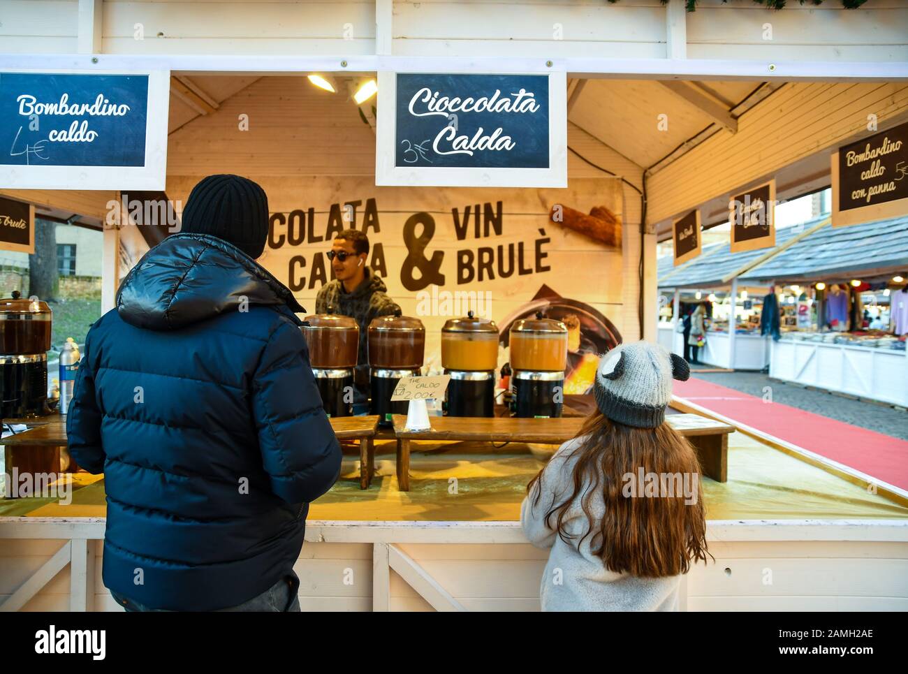 Vater und Tochter kaufen heiße Schokolade und Glühwein in einem Warmgetränkestall auf dem traditionellen Weihnachtsmarkt in Turin, Piemont, Italien Stockfoto