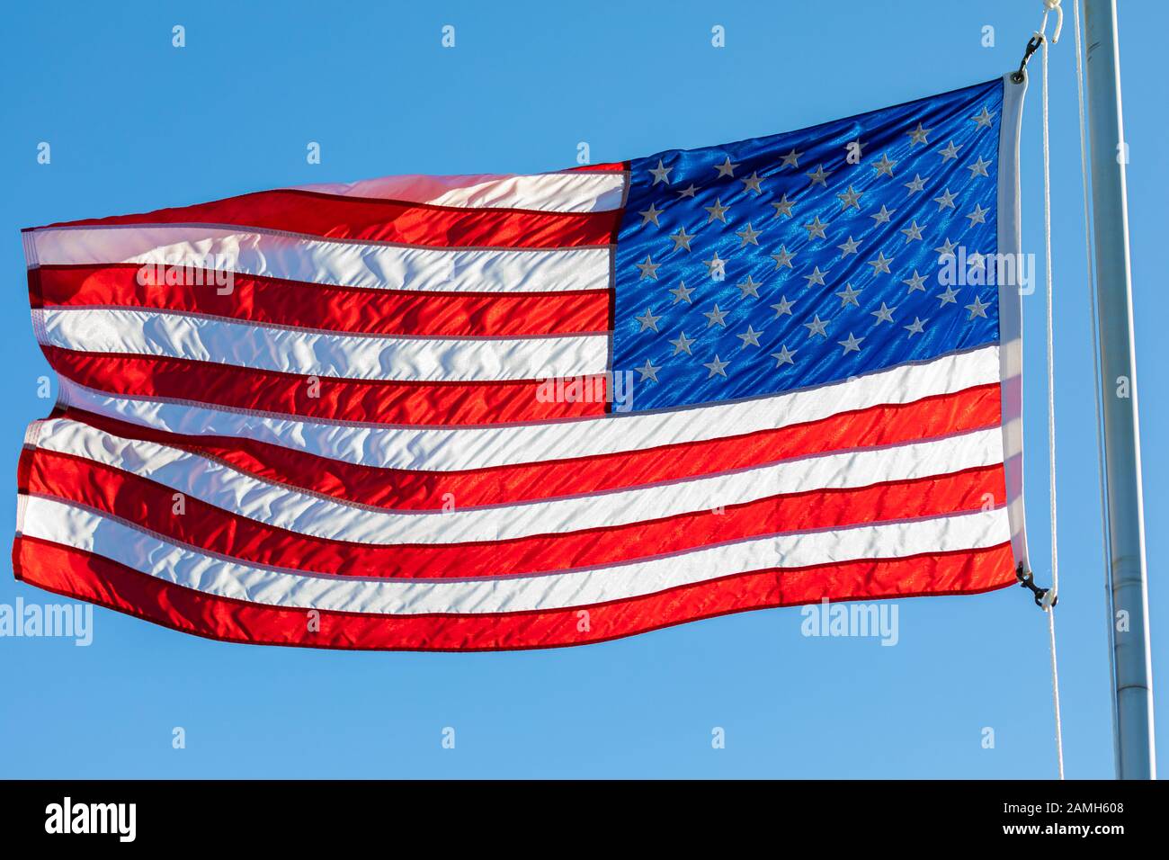 Amerikanische Flagge, von der untergehenden Sonne hinterleuchtet, winkt im Wind. Stockfoto