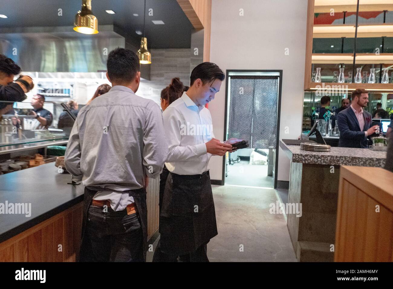 Kellner verwendet Tablett während der großen Eröffnungsveranstaltung im Bamboo Sushi, einem umweltverträglichen Restaurant in der City Center Bishop Ranch, San Ramon, Kalifornien, Dezember 2019. Bamboo Sushi war das erste Restaurant, das von der Green Restaurant Association als nachhaltig zertifiziert wurde, und das erste Restaurant, das den B Corp Status erhielt. () Stockfoto