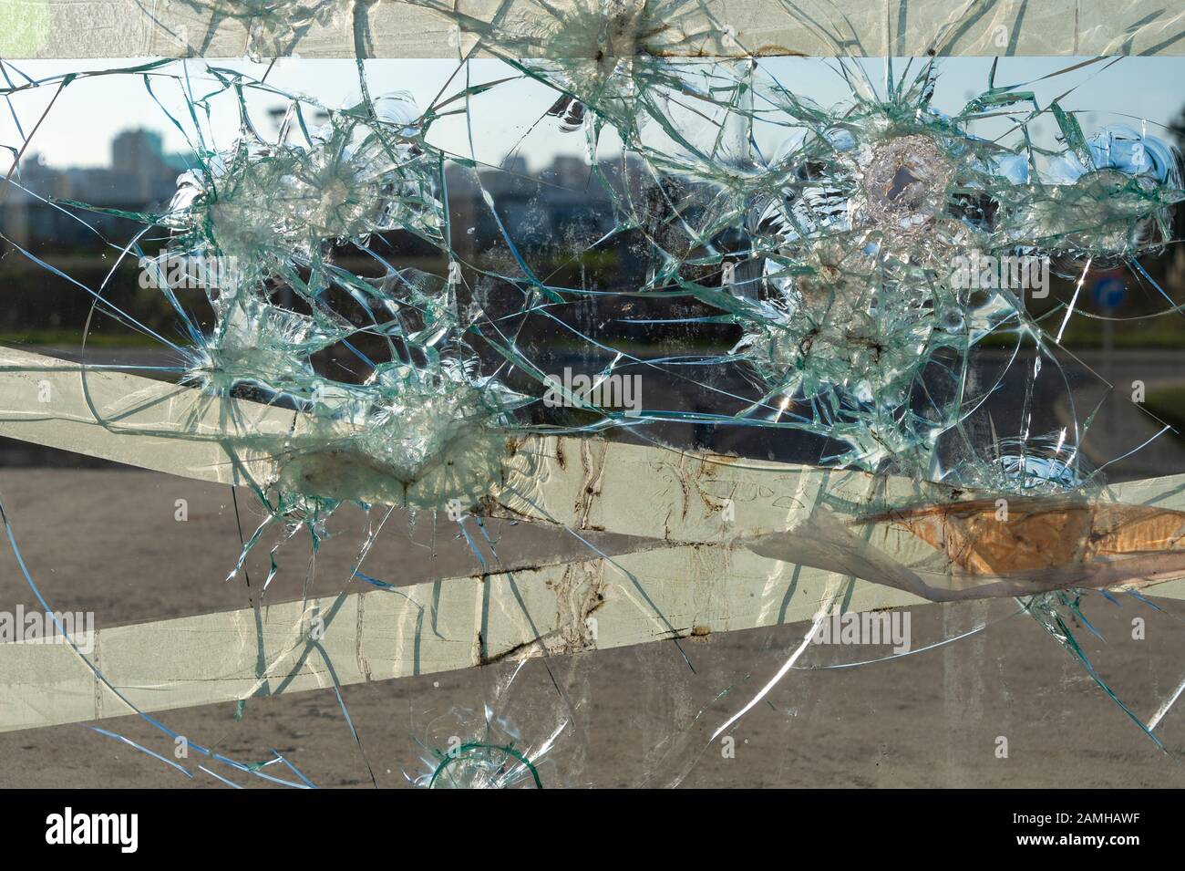 Schließen Sie das zerbrochene Glasfenster mit Rissen und Löchern Stockfoto