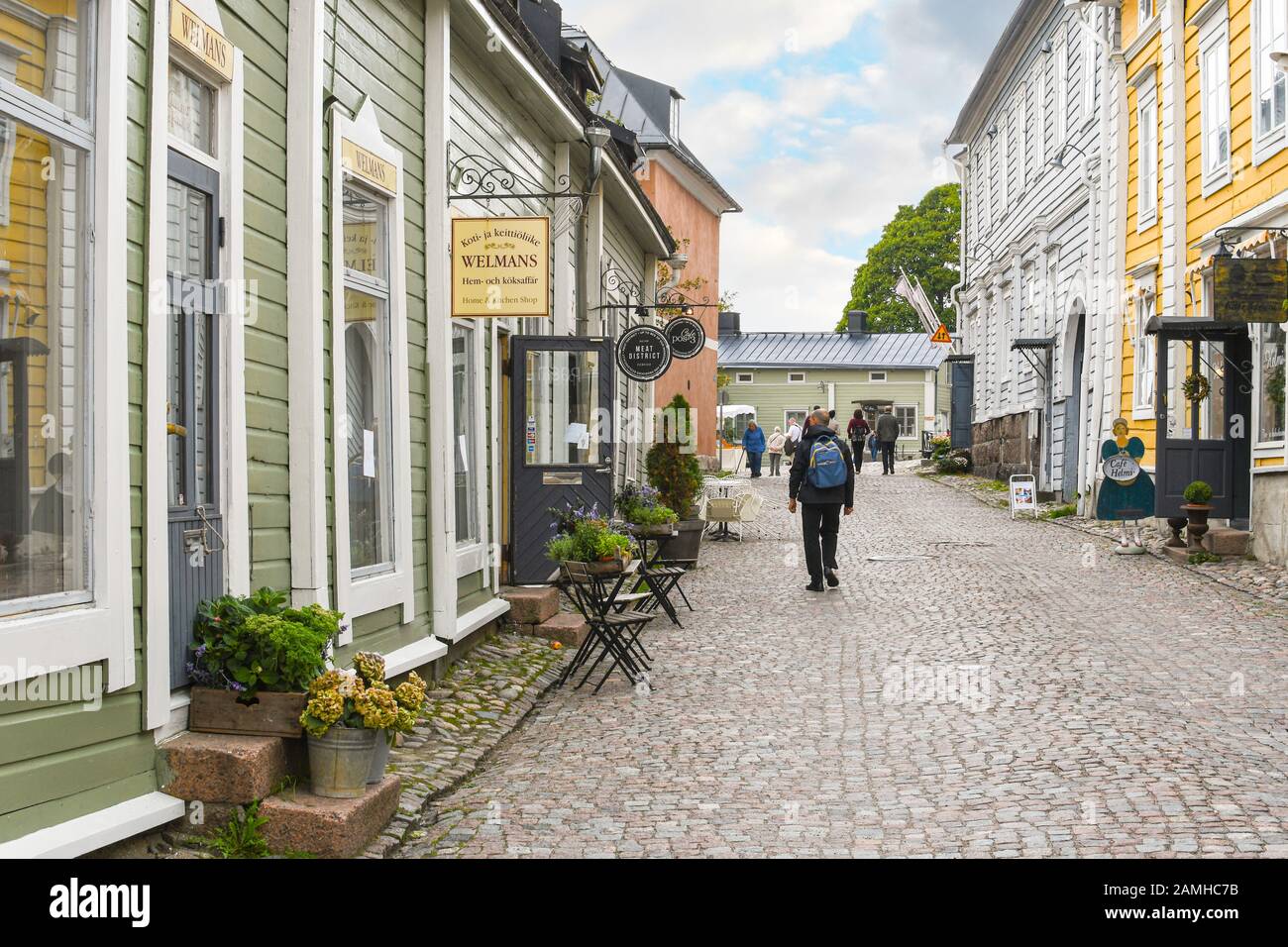 Touristen, darunter ein Mann mit Rucksack, gehen durch die Kopfsteinpflasterstraßen im historischen mittelalterlichen Dorf Porvoo, Finnland. Stockfoto