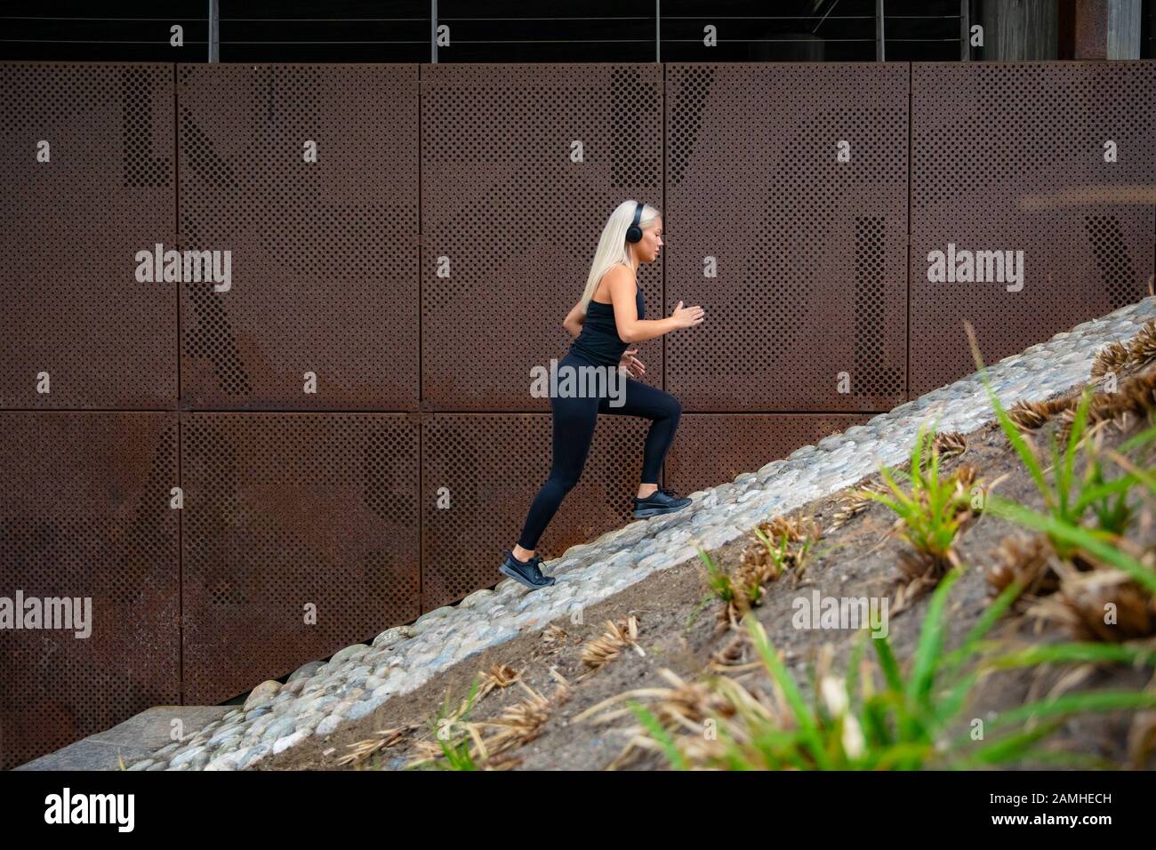 Passen Sie attraktive Sportfrauen, die schnell in Treppen gegen eine Metallwand in der Stadt laufen Stockfoto