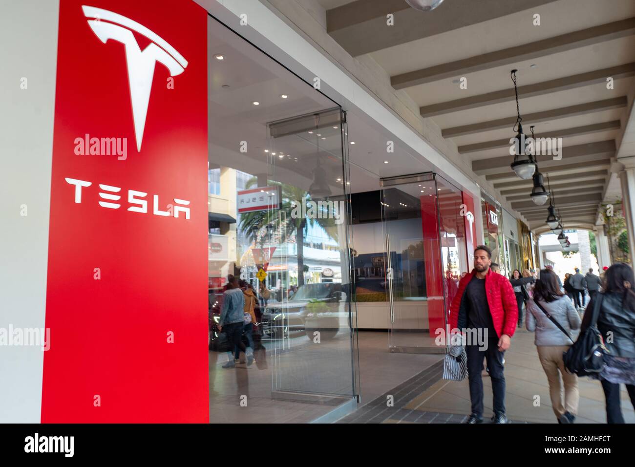 Am Tesla Motors Store in Santana Row im Silicon Valley, San Jose, Kalifornien, am 14. Dezember 2019 laufen Menschen an der Fassade mit Logo vorbei. () Stockfoto