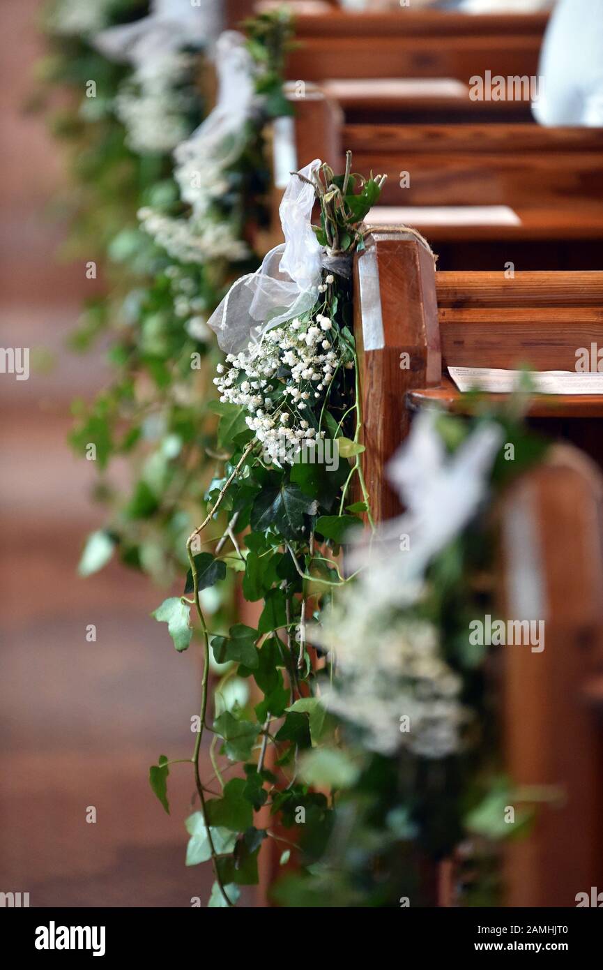 Auf den Kirchenbänken werden bei einer Hochzeit Blumen ausgestellt. Stockfoto