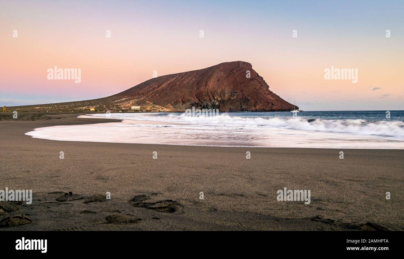 Sonnenuntergang am Strand La Tejita mit dem berühmten "Roten Hügel" (La Montaña Roja) im Süden von Teneras, Kanarische Inseln, Spanien. Stockfoto