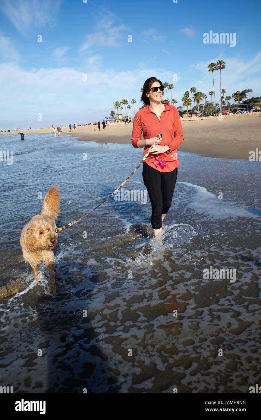 Junge Frau und Hund auf See in Corona del Mar State Beach Newport Beach, Südkalifornien USA Stockfoto