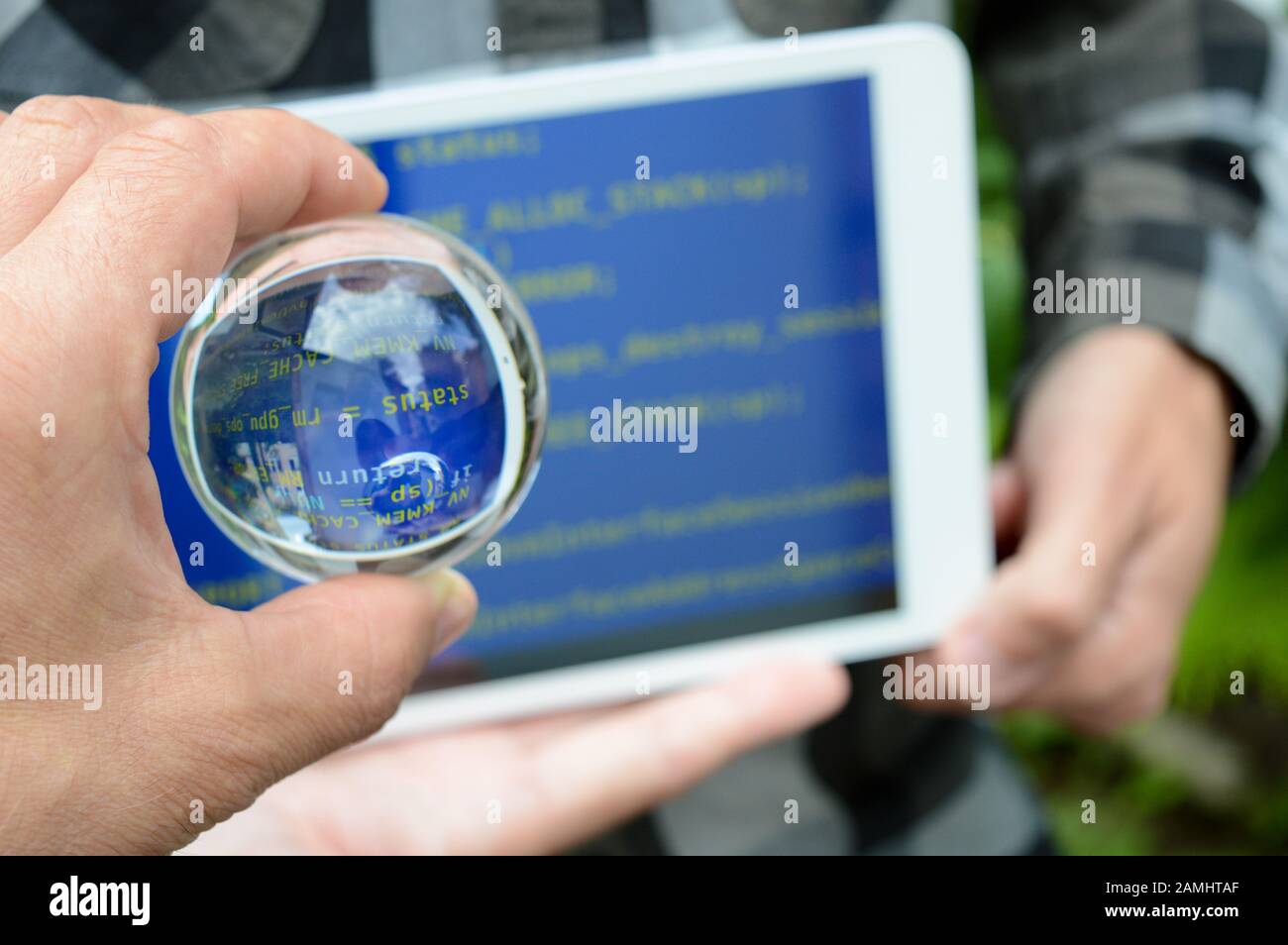 Kristallkugel in der Hand auf dem Hintergrund eines verschwommenen Tabletts mit blauem Bildschirm, das Reparaturverfahren nach Hacker-Angriffen, ein Warnkonzept Stockfoto
