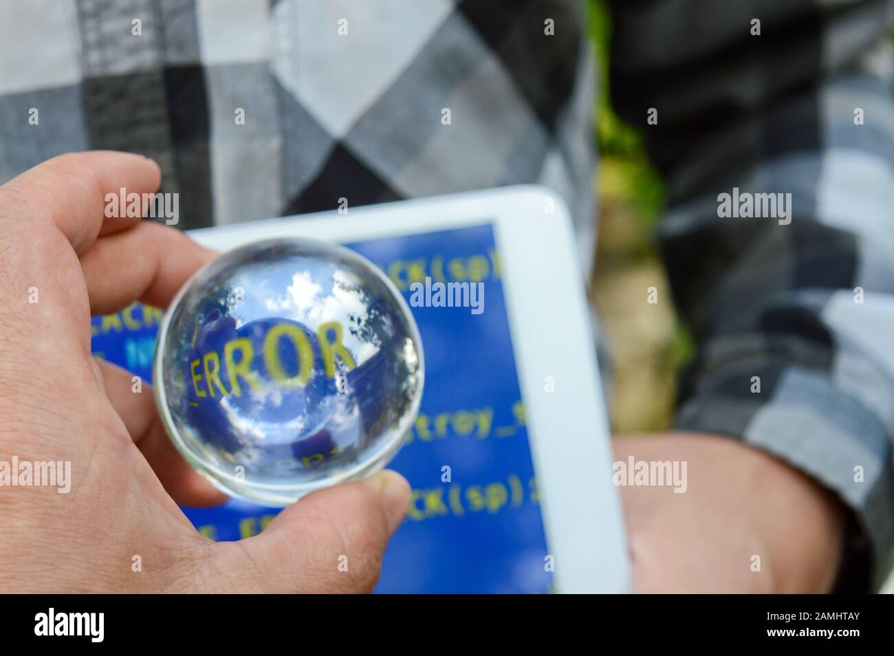 Kristallkugel in der Hand mit dem Wort "Fehler" auf dem Hintergrund eines Tabletts mit blauem Bildschirm, das Reparaturverfahren nach Hacker-Angriffen Stockfoto