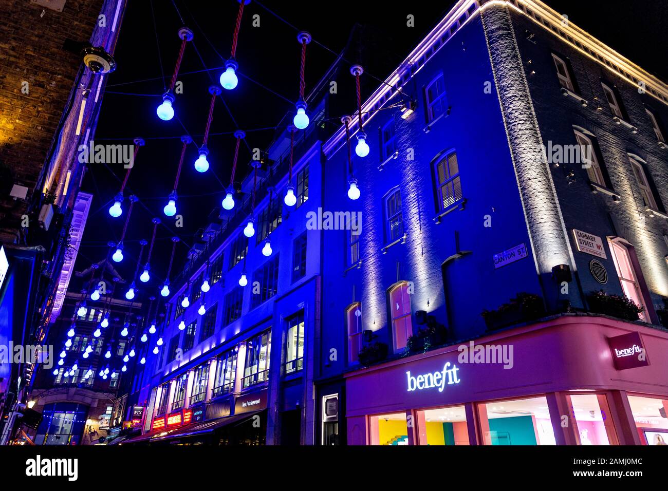 Nachts beleuchtete Gebäude und Lichtinstallation in der Carnaby Street, London, Großbritannien Stockfoto