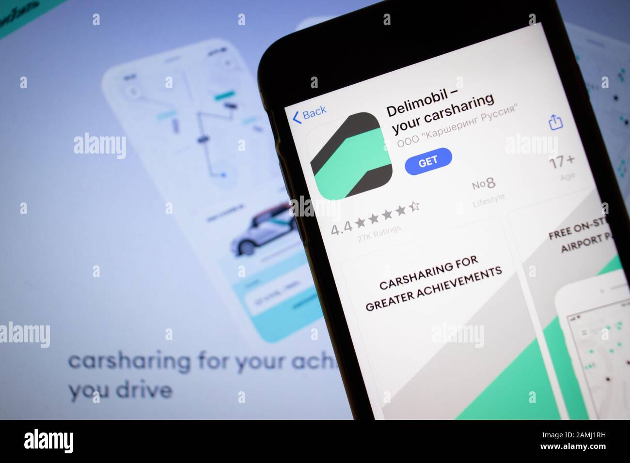 Petersburg, Russland - 10. Januar 2020: Mobiltelefon mit Delimobil Carsharing-Symbol auf dem Bildschirm Nahaufnahme mit Website auf Laptop, Illustration Stockfoto