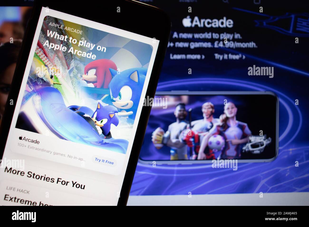 Petersburg, Russland - 10. Januar 2020: Handy mit Apple Arcade Seite im App-Store auf dem Bildschirm Nahaufnahme mit Website auf Laptop, Illustration Stockfoto