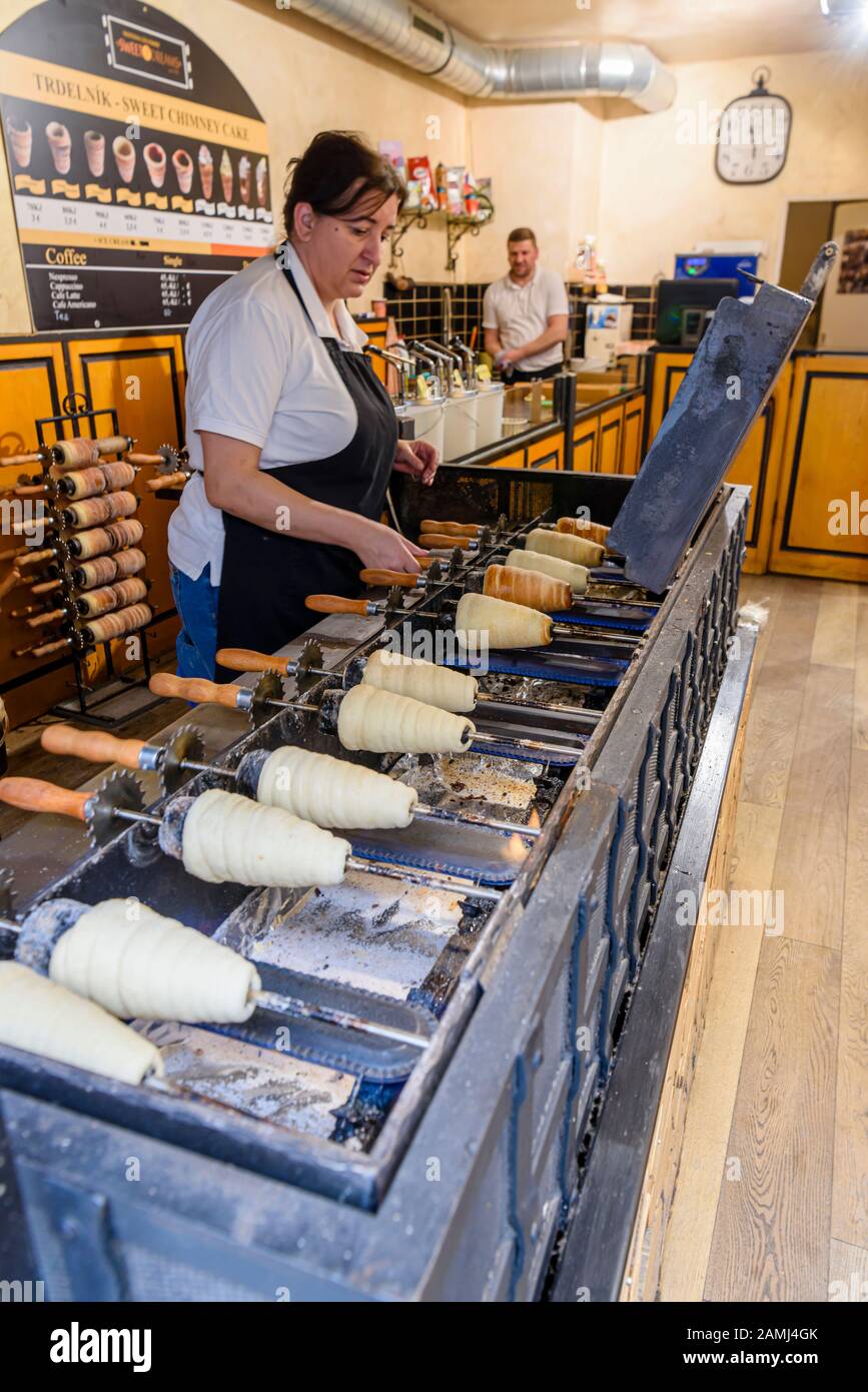 Cooking Trdelnik, ein traditioneller kegelförmiger Blätterteig, der auf einem Holzkegel zubereitet und mit Sahne, Zucker und Nüssen gefüllt ist, Prag, Tschechien Stockfoto