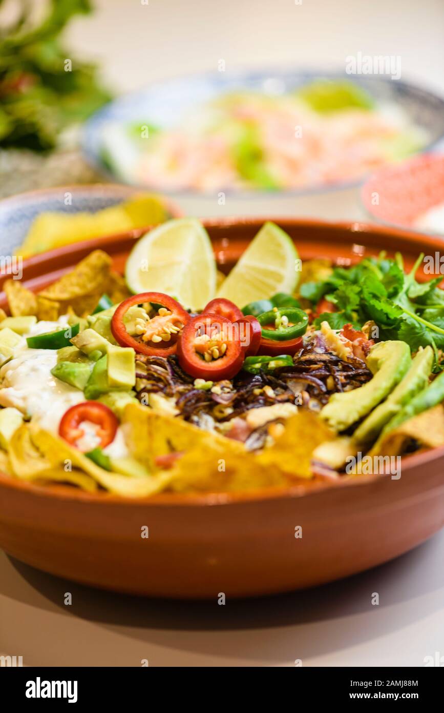 Mexikanische Mahlzeit mit Tortilla-Chips, Chilischuhn, Zwiebeln, Limetten, Koriander, Avocado und saurer Sahne Stockfoto