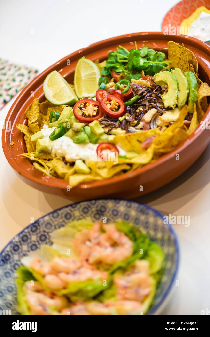 Mexikanische Mahlzeit mit Tortilla-Chips, Chilischuhn, Zwiebeln, Limetten, Koriander, Avocado und saurer Sahne Stockfoto