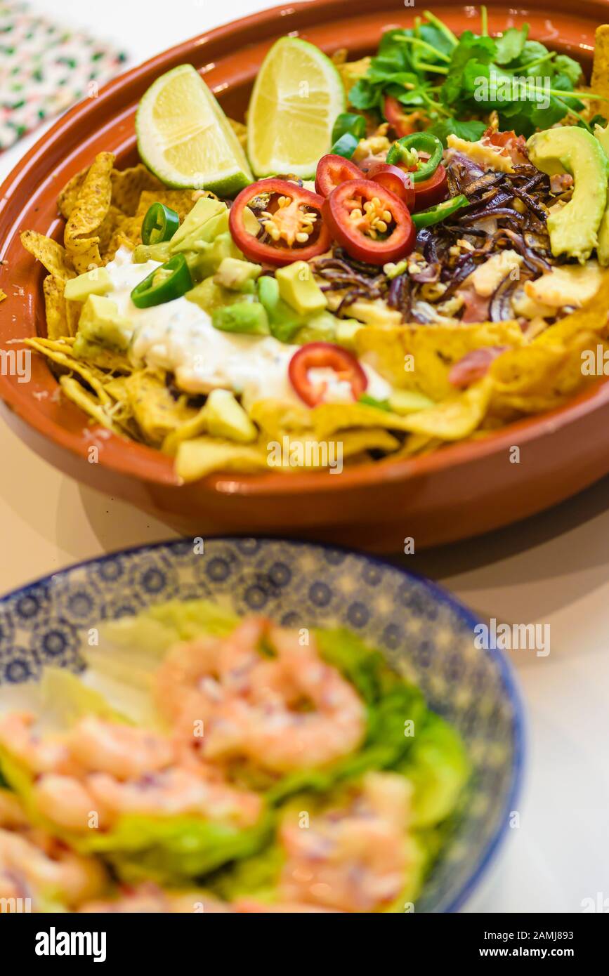 Mexikanische Mahlzeit mit Tortilla-Chips, Chilischuhn, Zwiebeln, Limetten, Koriander, Avocado und saurer Sahne Stockfoto