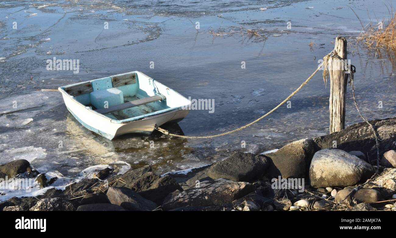 Kleines Schlauchboot im Winter an einem eisigen Ufer festgebunden. Stockfoto