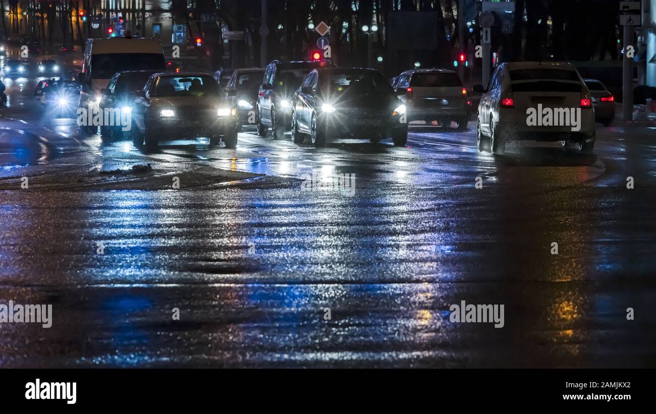 Autos in der Nacht City Street, nasse Straße nach dem ersten Schneefall Stockfoto
