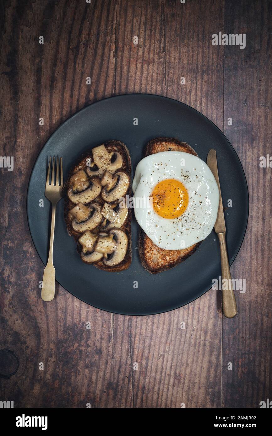 Pilze auf Toast und gebratenes Ei auf Toast. Mit einem Sauerteigbrot mit Kastanienpilzen Stockfoto