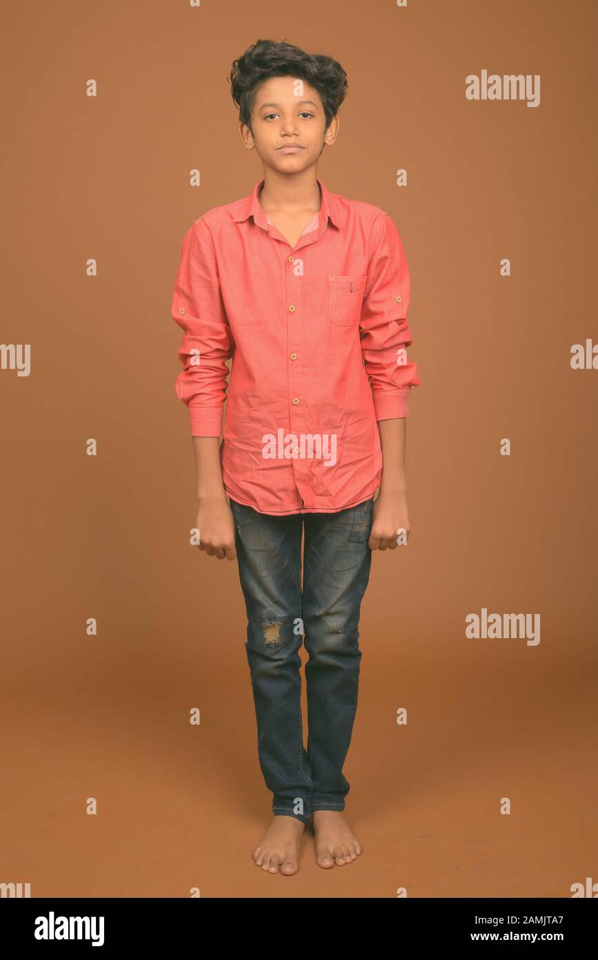 Studioshot des jungen indischen Jungen, der vor braunem Hintergrund elegante Freizeitkleidung trägt Stockfoto