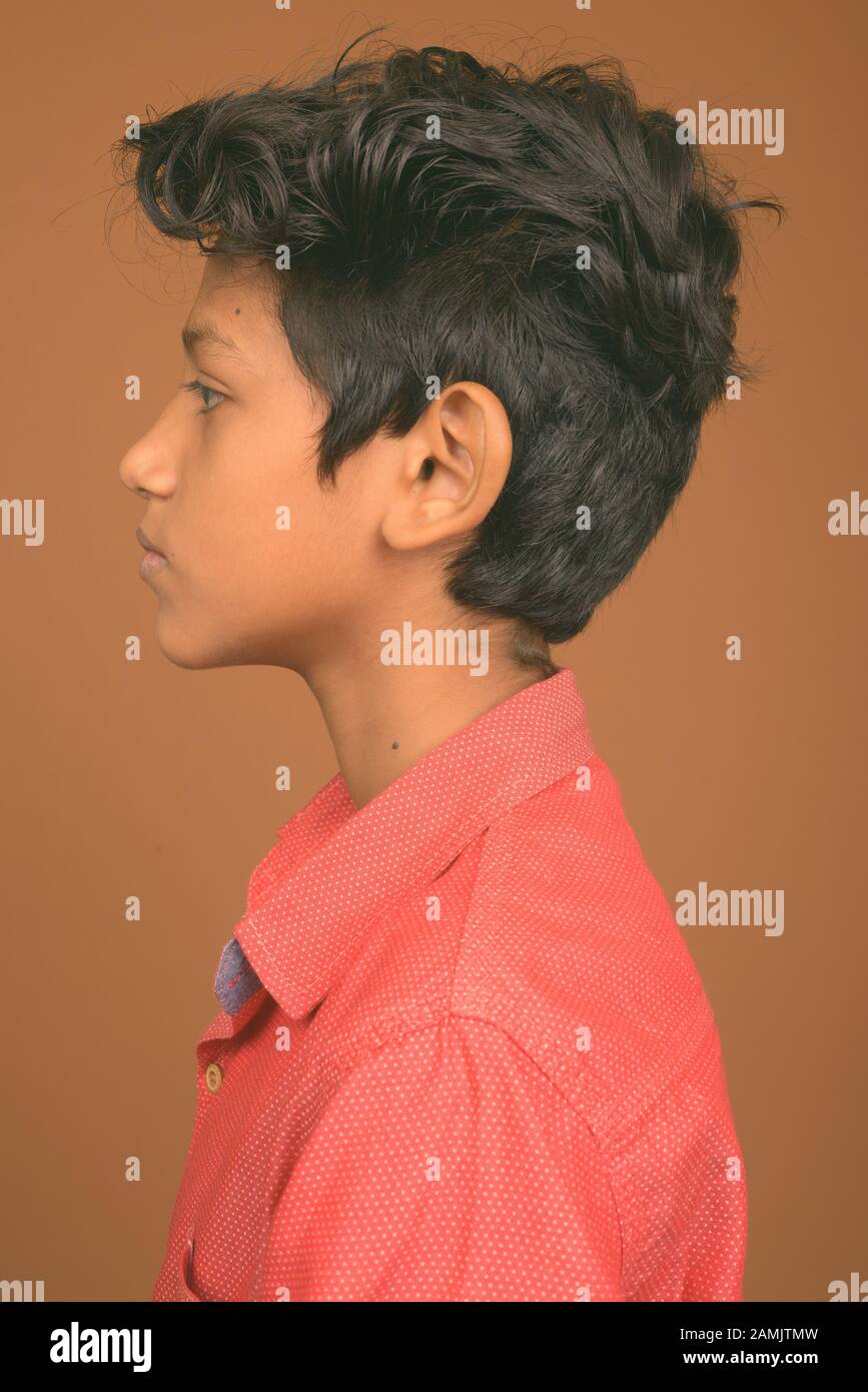 Studioshot des jungen indischen Jungen, der vor braunem Hintergrund elegante Freizeitkleidung trägt Stockfoto