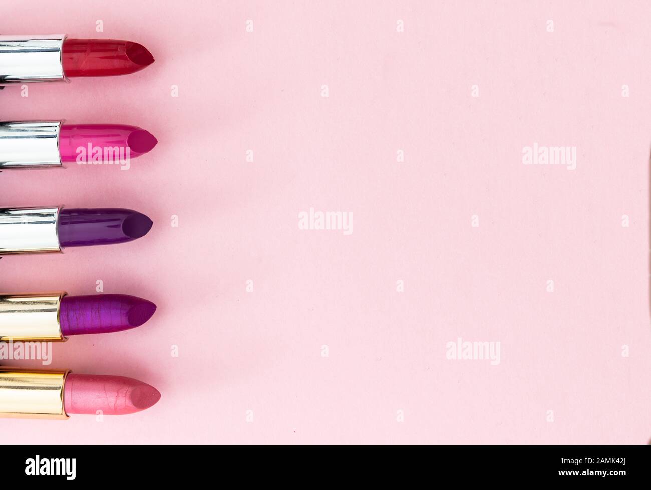 Lippenstifte setzen bunt vor rosa Hintergrund, Nahansicht. Leuchtende Farben Lippenglanz, Kosmetik, Makeup-Konzept Stockfoto