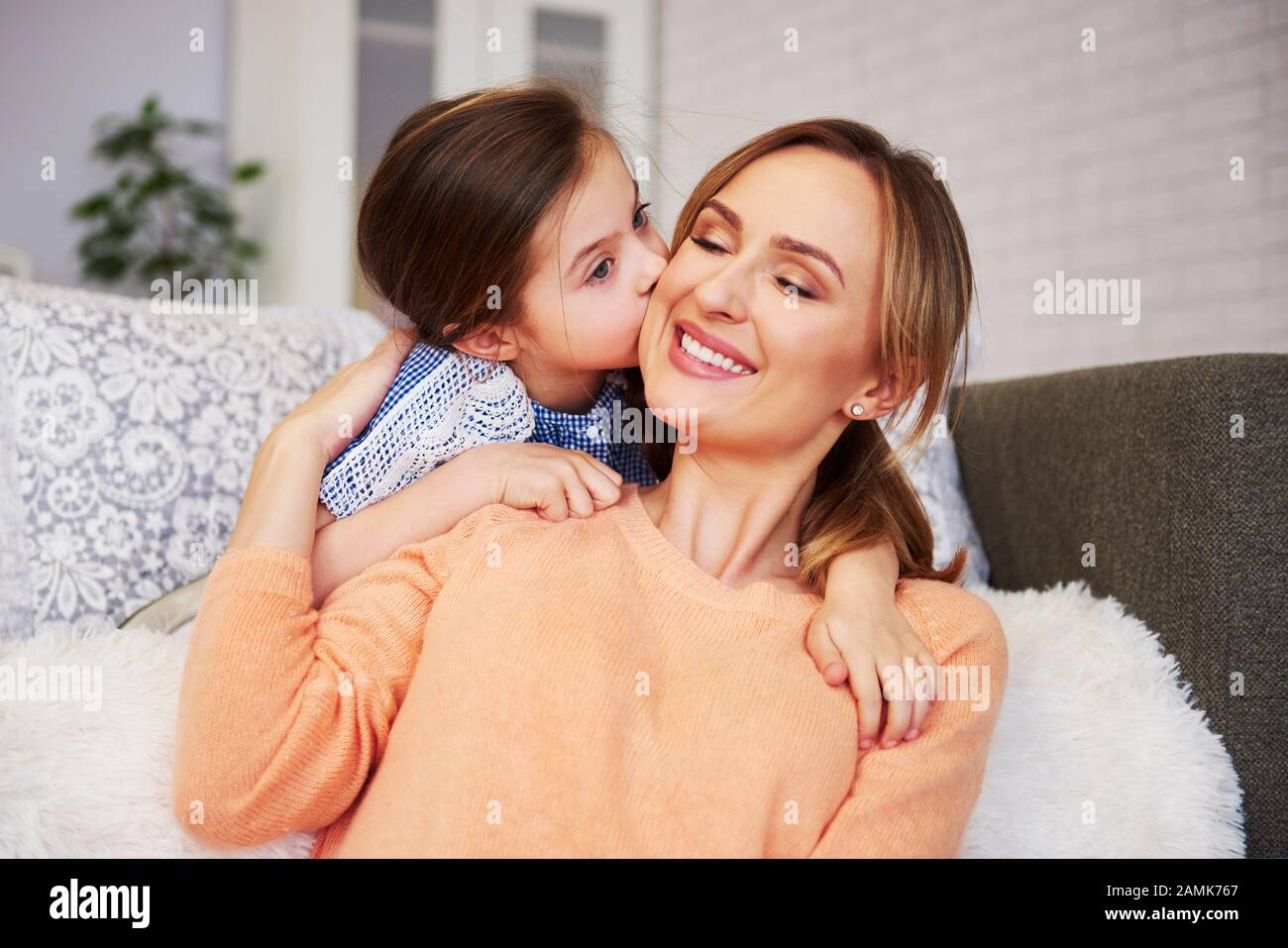 Das liebenswerte Mädchen, das ihre Mama auf die Wange küsst Stockfoto