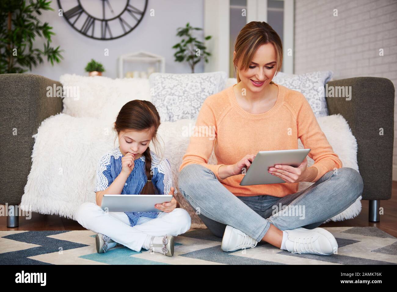 Mädchen und ihre Mutter benutzen ein Tablett im Wohnzimmer Stockfoto